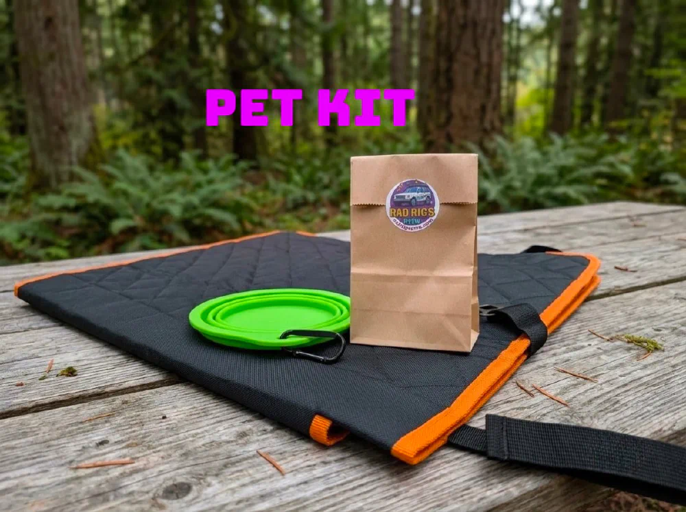 Pet kit laid out on a picnic table: a quilted roll-up pet mat with orange trim and carry strap, a collapsible green bowl on a carabiner, and a Rad Rigs treat bag